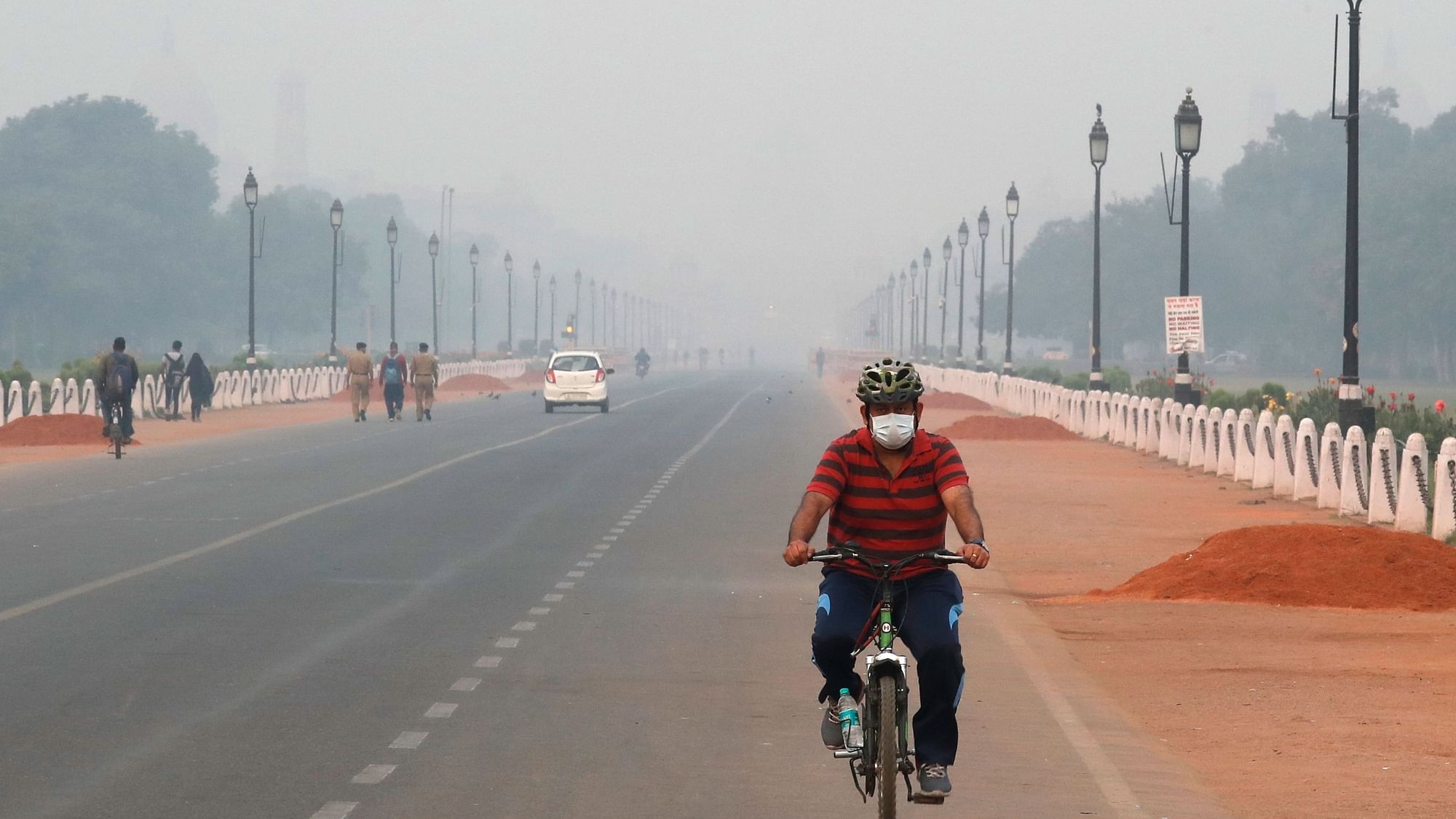 A man cycles wearing a pollution mask early morning amidst light smog in New Delhi.