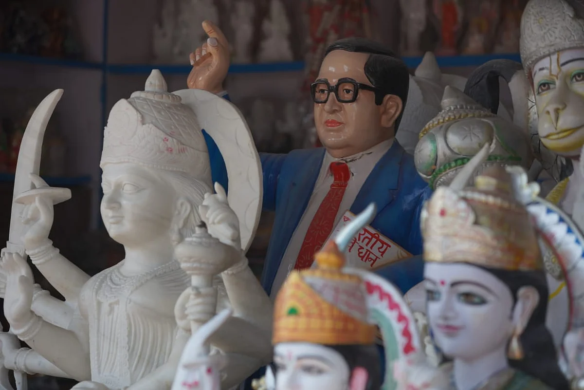 A statue of BR Ambedkar stands amidst the statues of gods and goddesses in the shop.