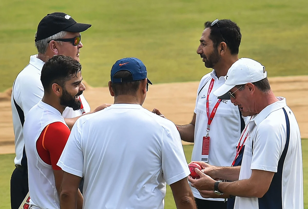 Umpires check out the new pink ball as India’s captain Virat Kohli, watches after batting in the nets during a training session ahead of their first cricket test match against Bangladesh in Indore.