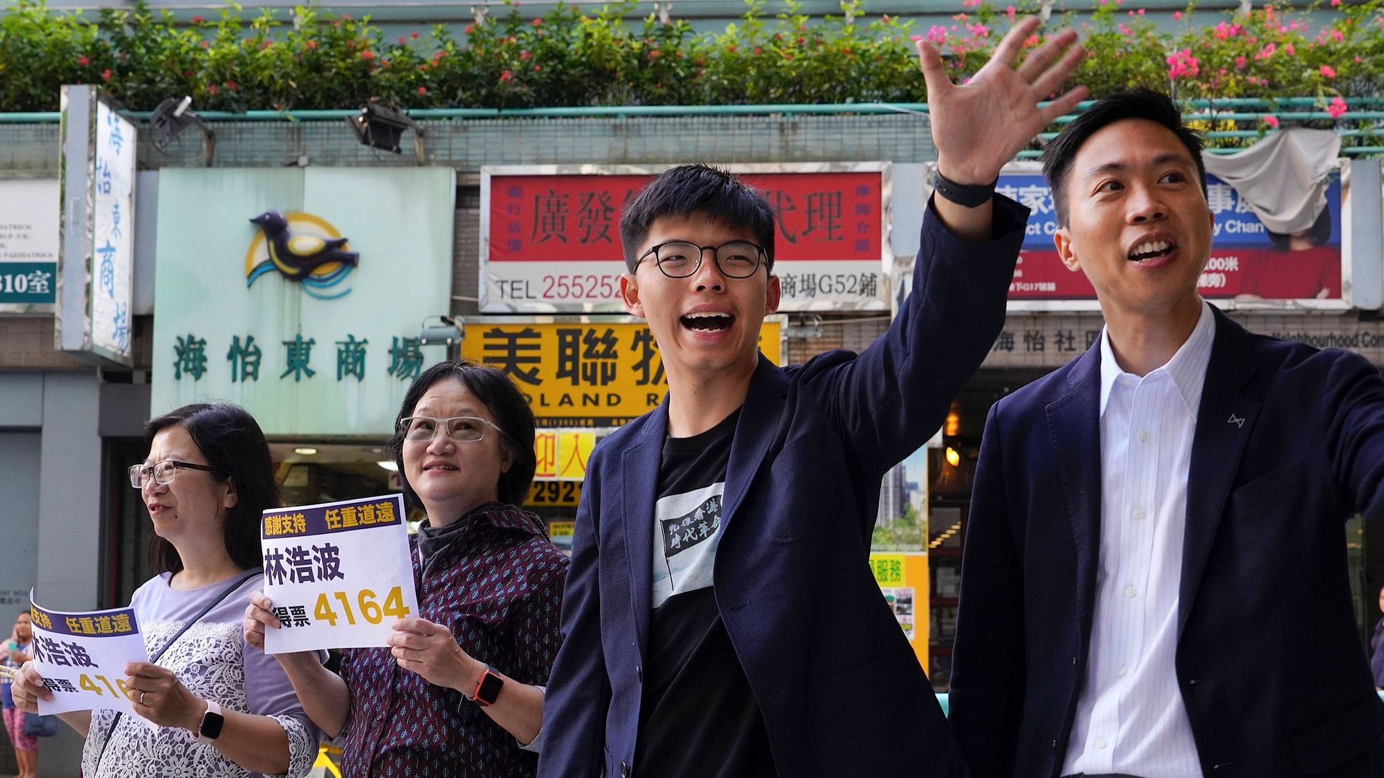 Election winner candidate Kelvin Lam, right, and pro-democracy activist Joshua Wong, second right, wave to people and thank for their support, outside South Horizons Station in Hong Kong, Monday, 25 November.