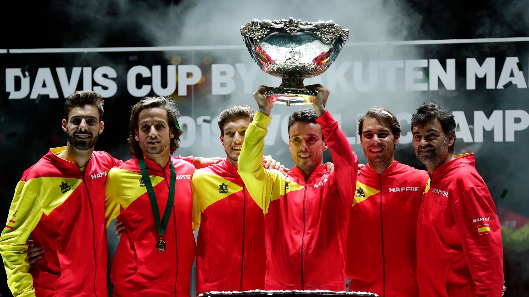 Spain’s Roberto Bautista Agut lifts the trophy as the Spanish team poses after Spain defeated Canada 2-0 to win the Davis Cup final in Madrid, Spain, Sunday.