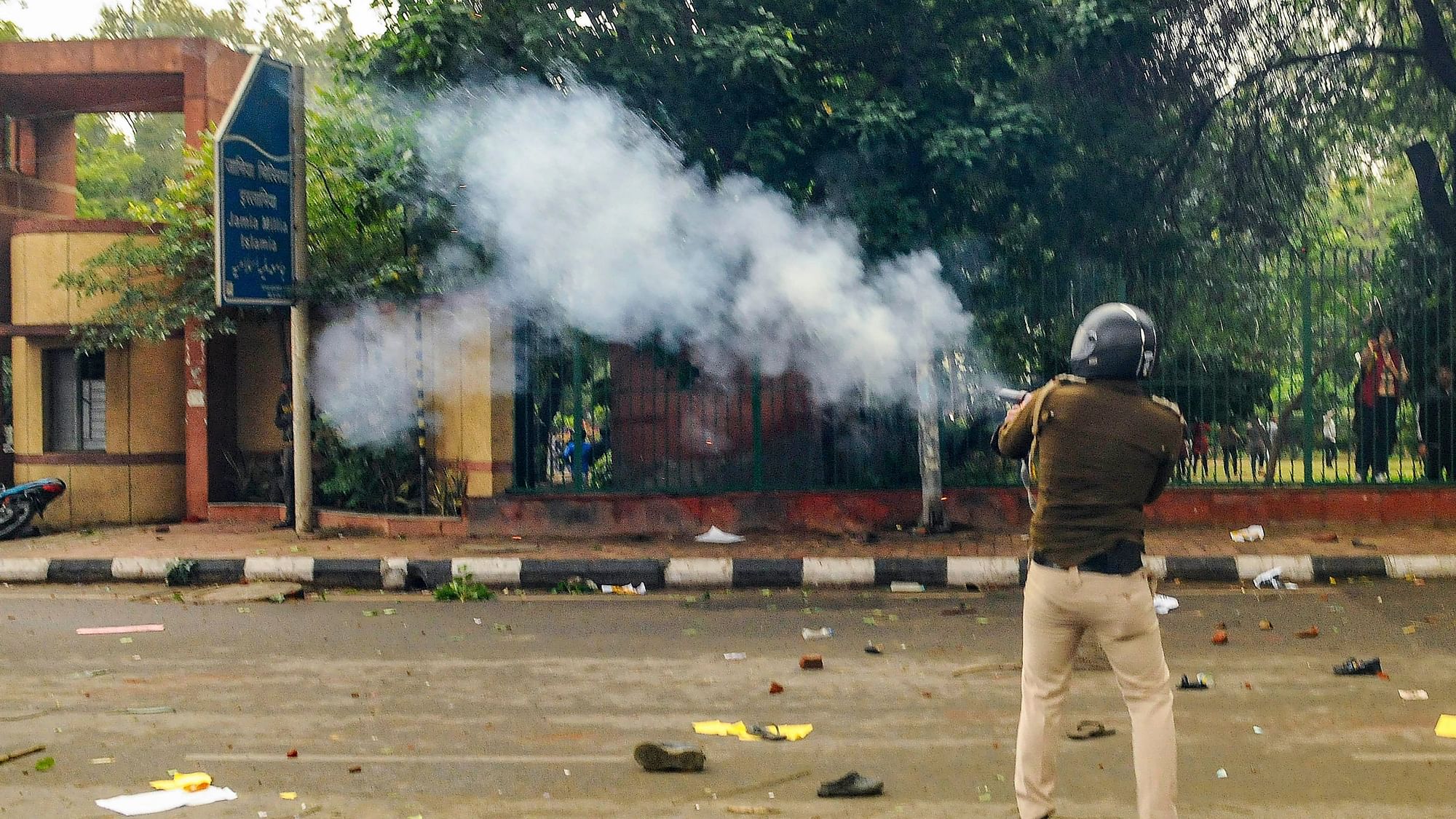A police personnel fires tear gas as students of Jamia Millia Islamia University stage a protest against the passing of Citizenship Amendment Bill, in New Delhi on Friday 13 December.
