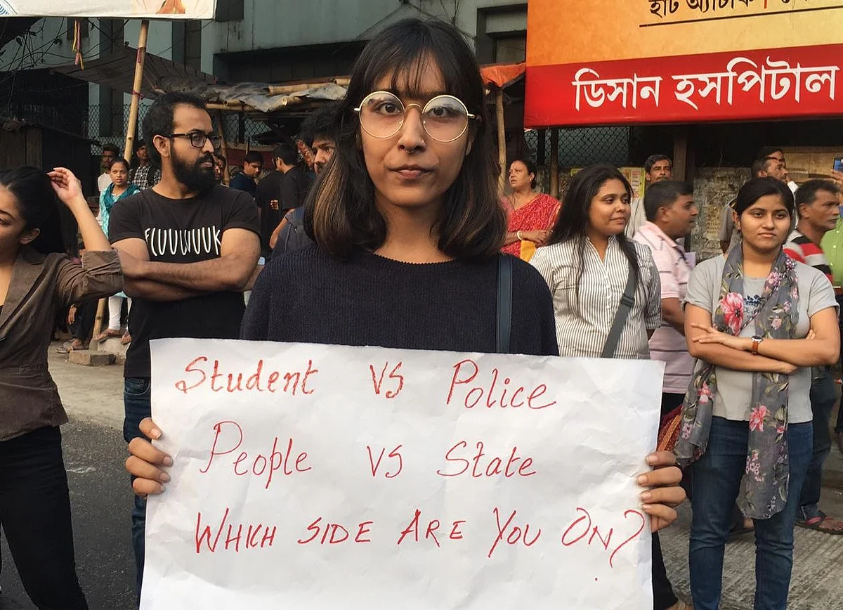 A protester outside Jadavpur University holds up a placard referencing Sunday’s violence in Jamia Millia Islamia.