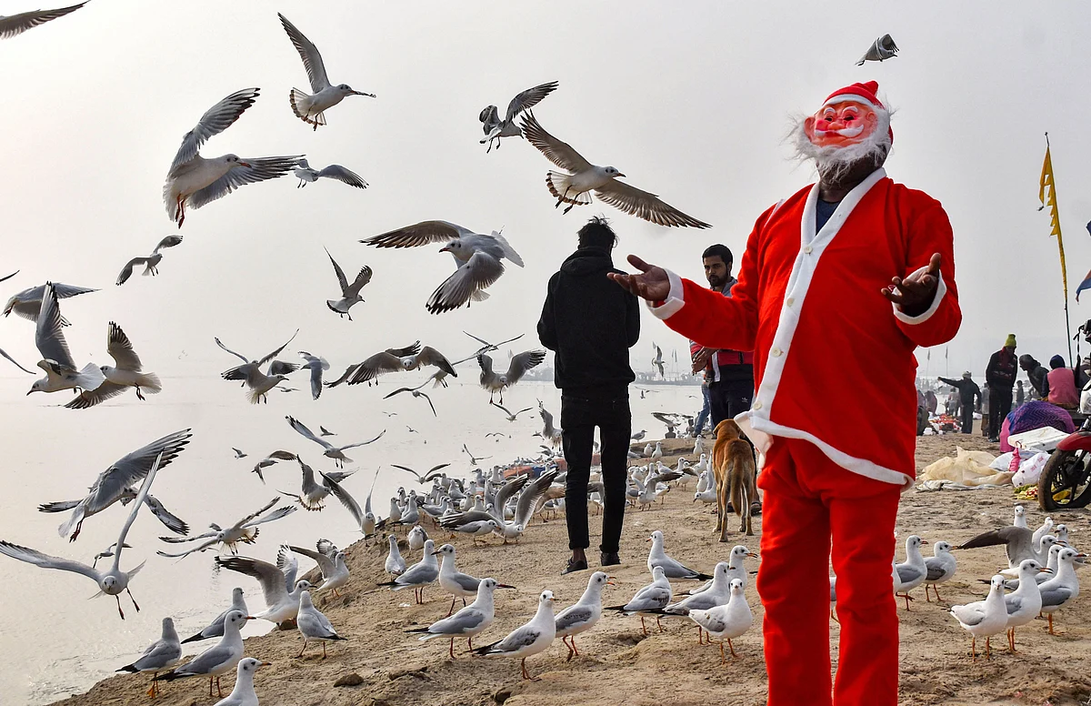 A man dressed like Santa Claus feeds gulls at Sangam on Christmas, in Prayagraj on Wednesday. 25 December.