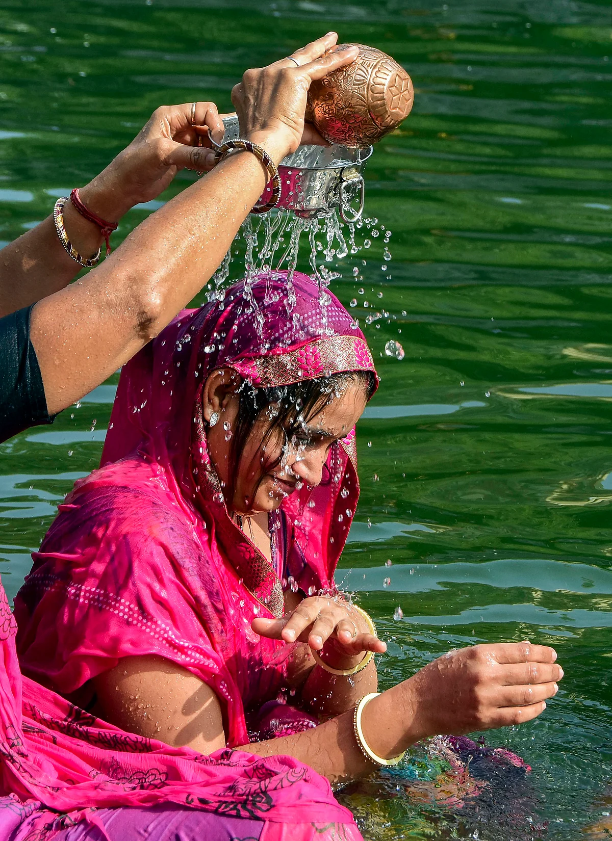 Devotees perform a traditional bathing ritual during the solar eclipse as they stand in the waters of Banganga Tank in Mumbai on Thursday, 26 December.