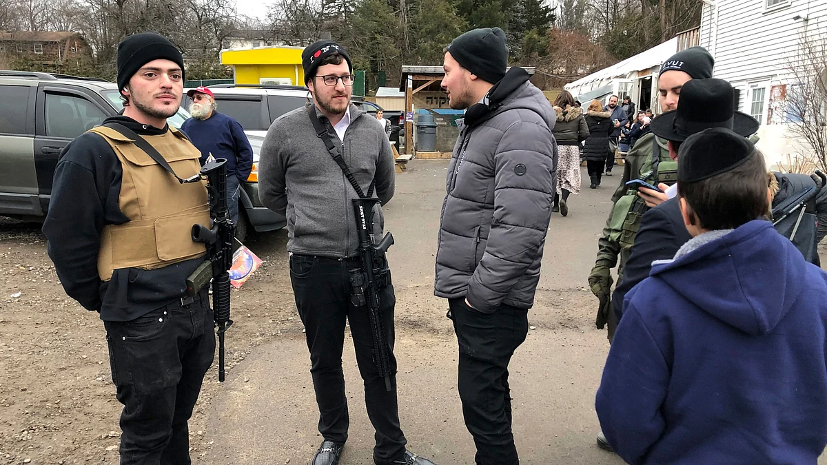 Armed members of the Jewish community stand guard at a celebration, Sunday, 29 December 2019, in Monsey, NY. A day earlier, a knife-wielding man stormed into a rabbi’s home and stabbed multiple people as they celebrated Hanukkah in the Orthodox Jewish community.