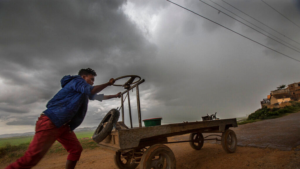A street vendor makes his way home under stormy skies in Antananarivo, Madagascar, on Monday, 9 December, 2019.