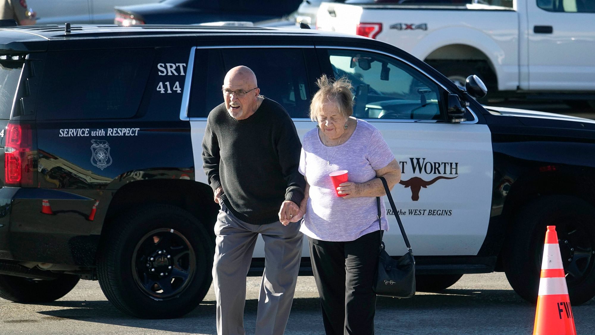 An elderly couple walks from West Freeway Church of Christ hours after a fatal shooting at the church in White Settlement, Texas.