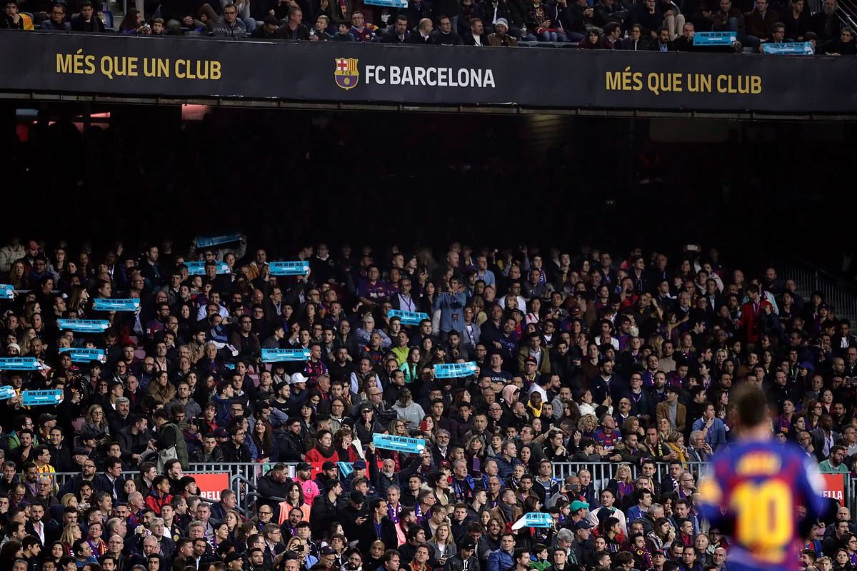 Barcelona’s Lionel Messi stands on the pitch while spectators hold up signs with the message” Spain, sit and talk” during a Spanish La Liga soccer match between Barcelona and Real Madrid at Camp Nou stadium.