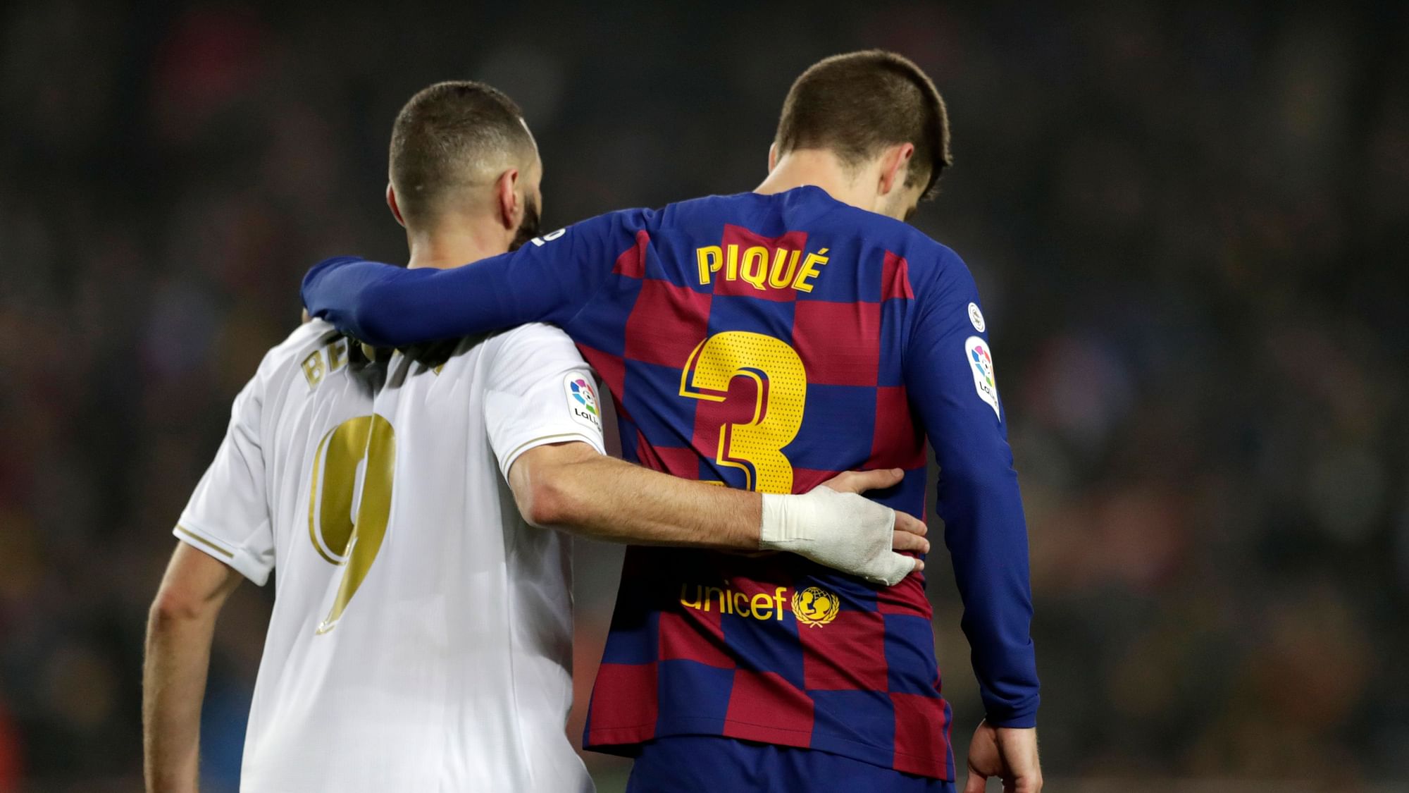 Real Madrid’s Karim Benzema, left, and Barcelona’s Gerard Pique walks together on the pitch during a Spanish La Liga soccer match between Barcelona and Real Madrid at Camp Nou stadium in Barcelona, Spain, Wednesday, Dec. 18, 2019.&nbsp;