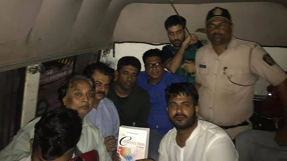 Activist Fahad Ahmad (right) holds up a copy of the Constitution. Kannan Gopinathan, who was also detained along with Ahmad, looks on.