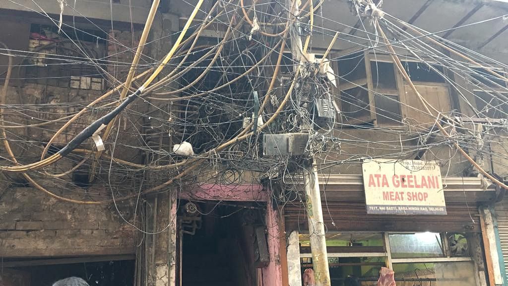 Old and tangled cables running close to residential buildings at Anaj Mandi in Delhi.