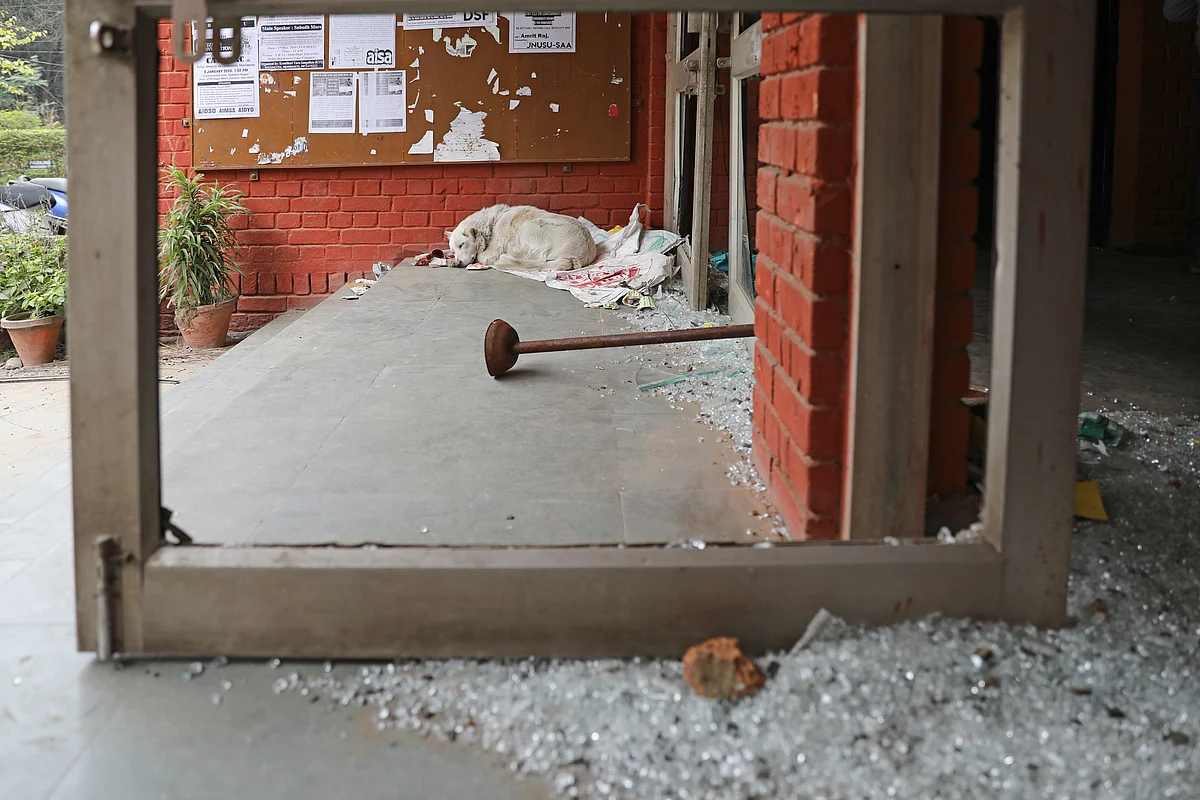 A dog rests next to glass scattered near the entrance to the Sabarmati hostel which was vandalised in Sunday’s assault by masked assailants at the Jawaharlal Nehru University in New Delhi, on Monday, 6 January.