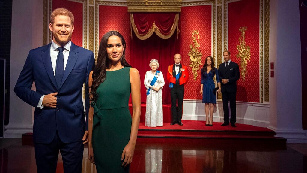 The figures of Britain’s Prince Harry and Meghan, Duchess of Sussex, left, are moved from their original positions next to Queen Elizabeth II, Prince Philip and Prince William and Kate, Duchess of Cambridge, at Madame Tussauds in London,