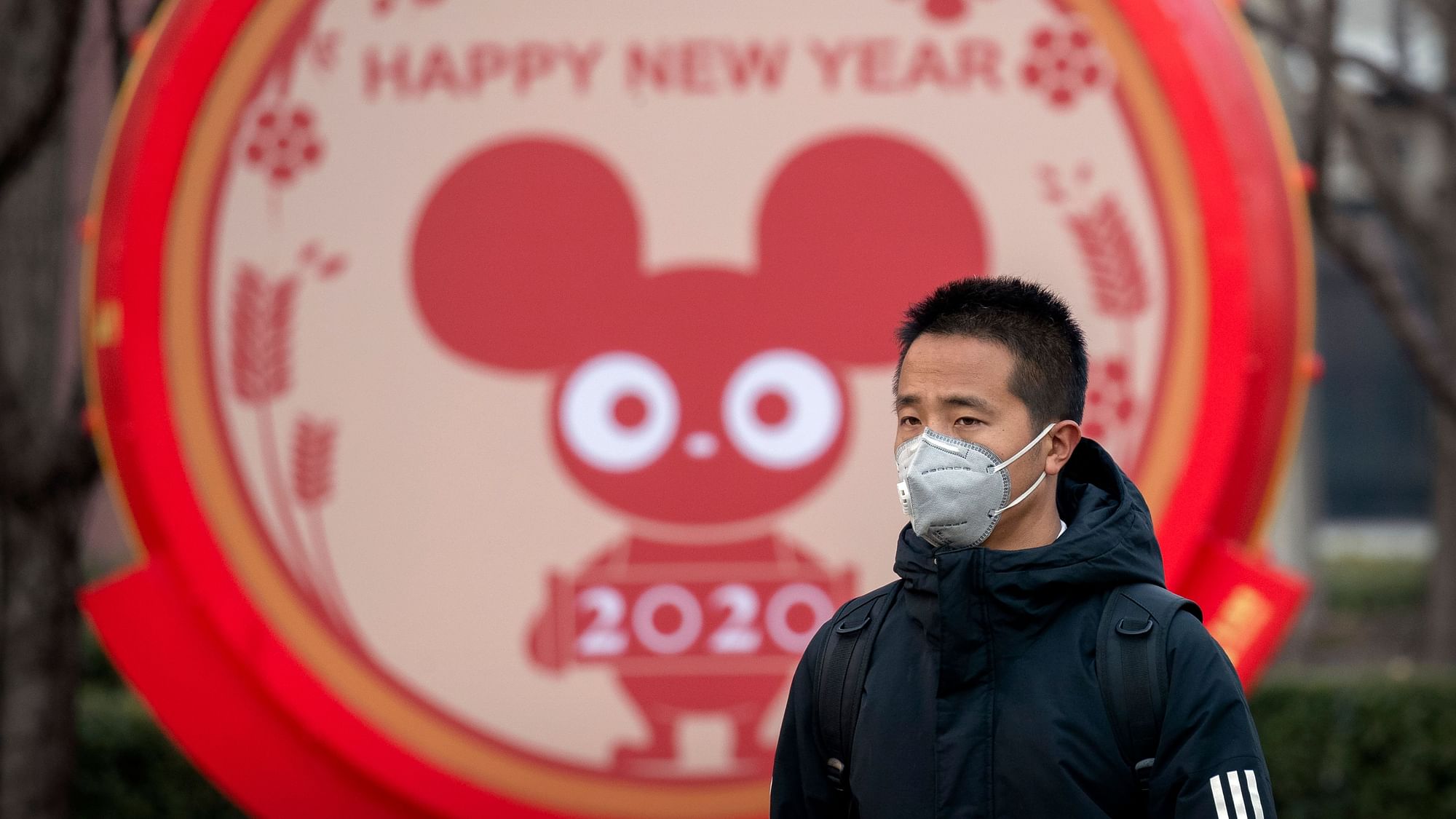 A man wears a face mask as he walks past a display for the upcoming Lunar New Year, the Year of the Rat, in Beijing on 22 January.