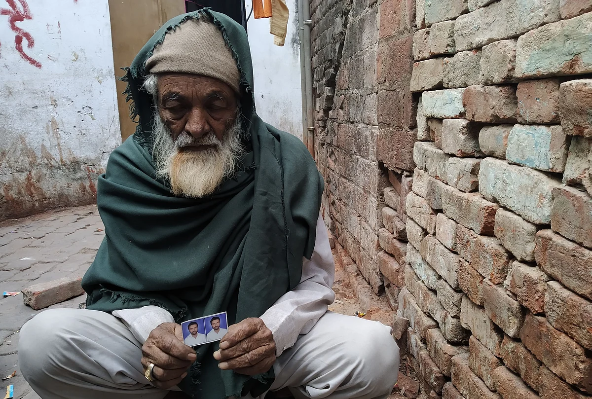 Mohammed Shareef sitting outside his house in Babupurwa with a photo of his son Raees who died allegedly due to police firing.