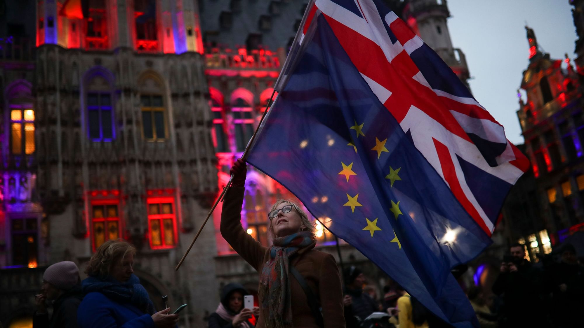 A woman holds up the Union and the European Union flags during an event called “Brussels calling” to celebrate the friendship between Belgium and Britain at the Grand Place in Brussels, on Thursday, January 30.