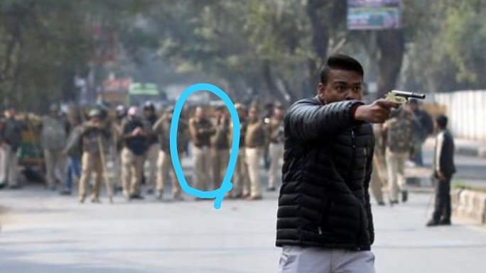 Delhi Police stands in the background as a man brandishes a gun at the anti-CAA protesters outside Jamia Millia Islamia on Thursday, 30 January.