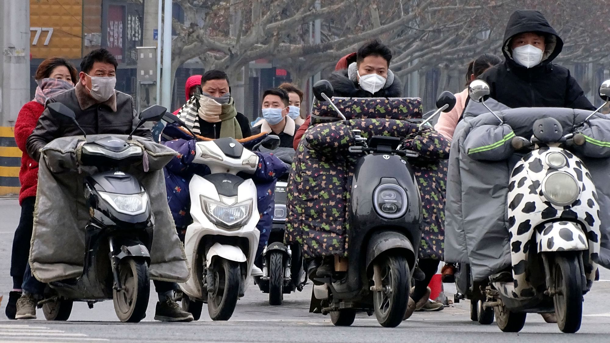 Scooter drivers wear face masks as they wait to cross an intersection in Fuyang in central China&apos;s Anhui province, Saturday, Jan. 25, 2020.