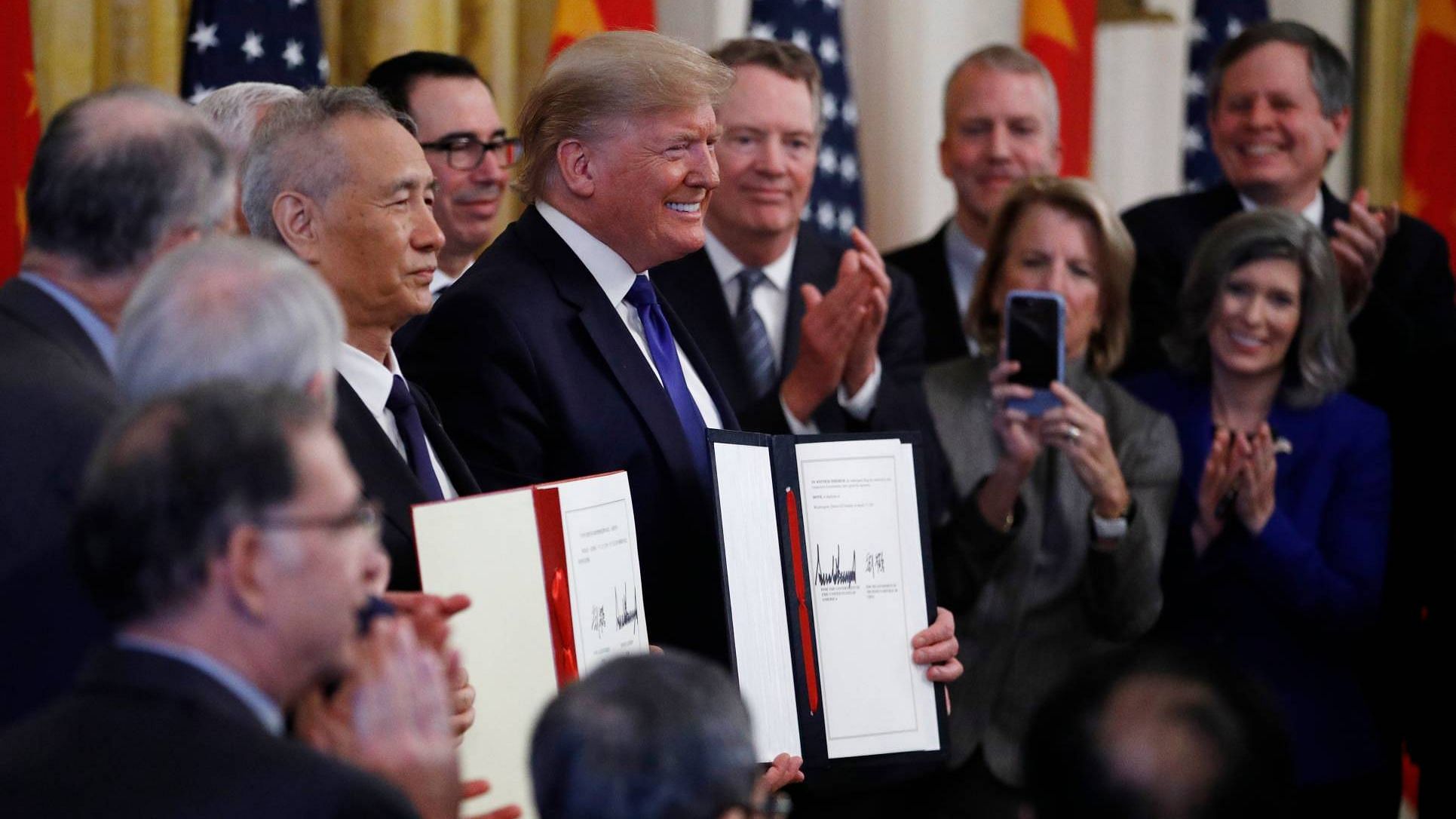 President Donald Trump, center, and Chinese Vice Premier Liu He, left, hold the US China Trade Agreement after signing it in the East Room of the White House on Wednesday, 15 January.