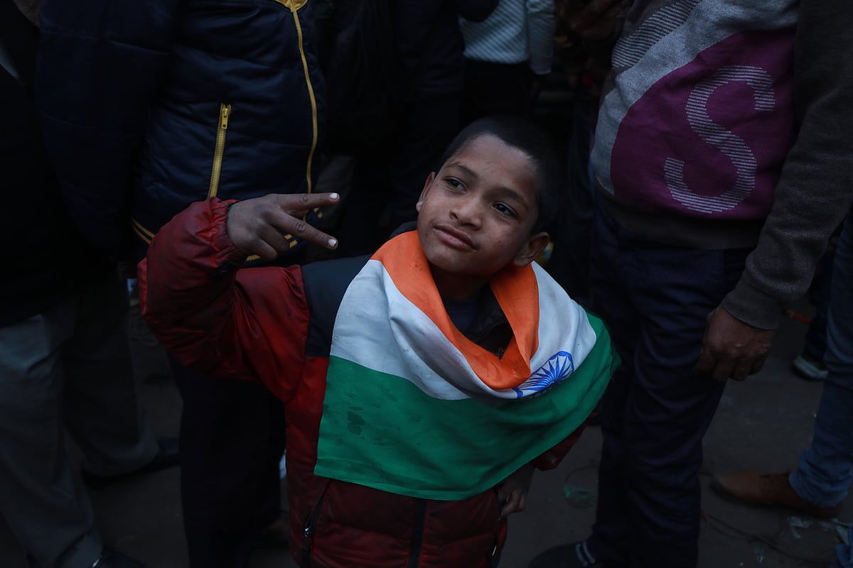 A boy wears the Indian flag around his neck and poses for the camera.&nbsp;