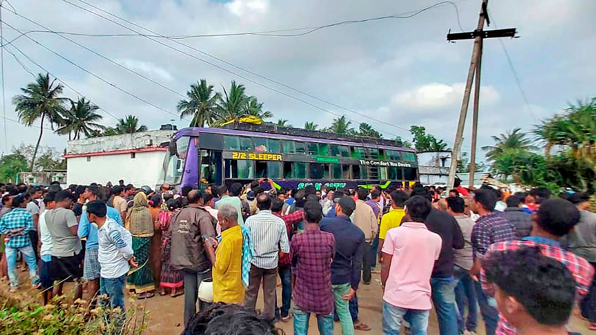 People look on to the bus which caught fire after coming in contact with a power transmission line at Golanthara .