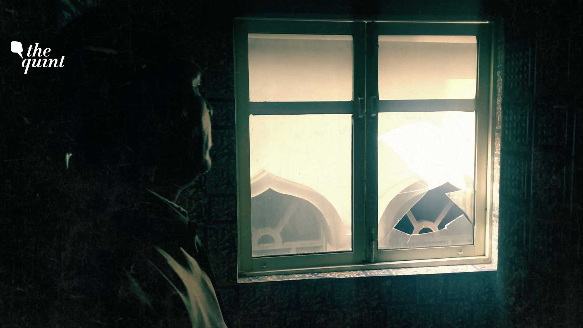 Ali Ahmed looks at the vandalised mosque from the broken window of his residence in Karawal nagar in northeast Delhi.