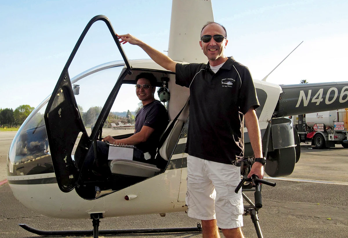 This undated file photo provided by Group 3 Aviation shows helicopter pilot Ara Zobayan standing outside a helicopter.