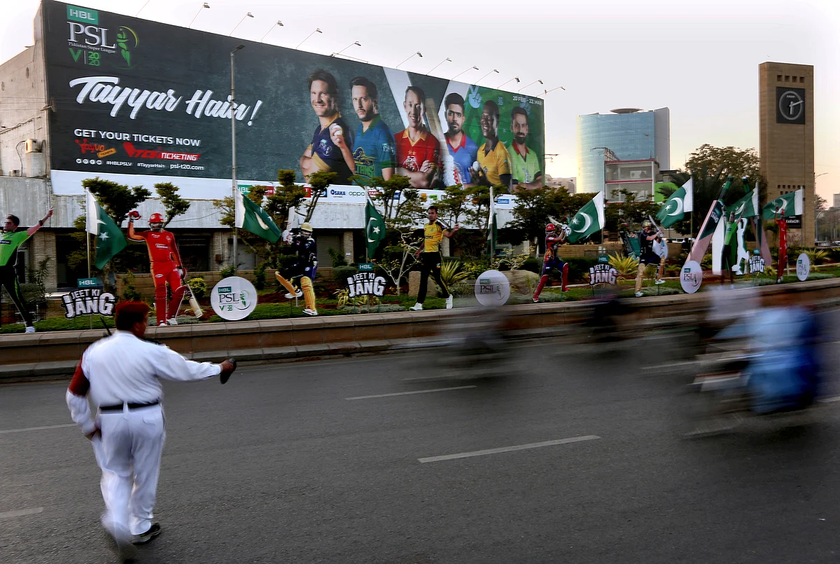 In this Saturday, Feb. 15, 2020 photo, a traffic police officer control traffic infant of huge billboard of cricketers displays along roadside in preparation of the upcoming Pakistan Super League, in Karachi, Pakistan. 