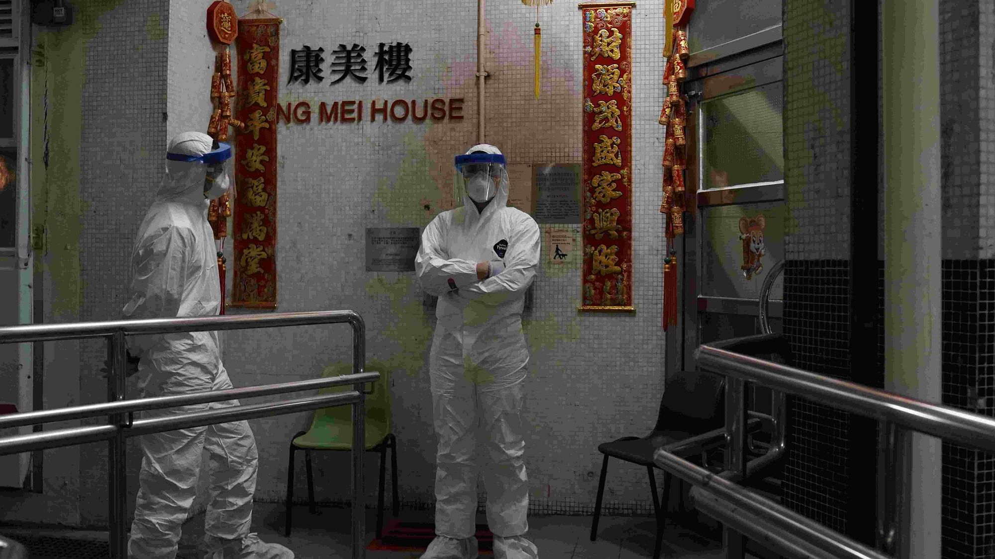People wearing protective suits stand near an entrance at the Cheung Hong Estate during evacuation of residents in Hong Kong on 11 February.&nbsp;