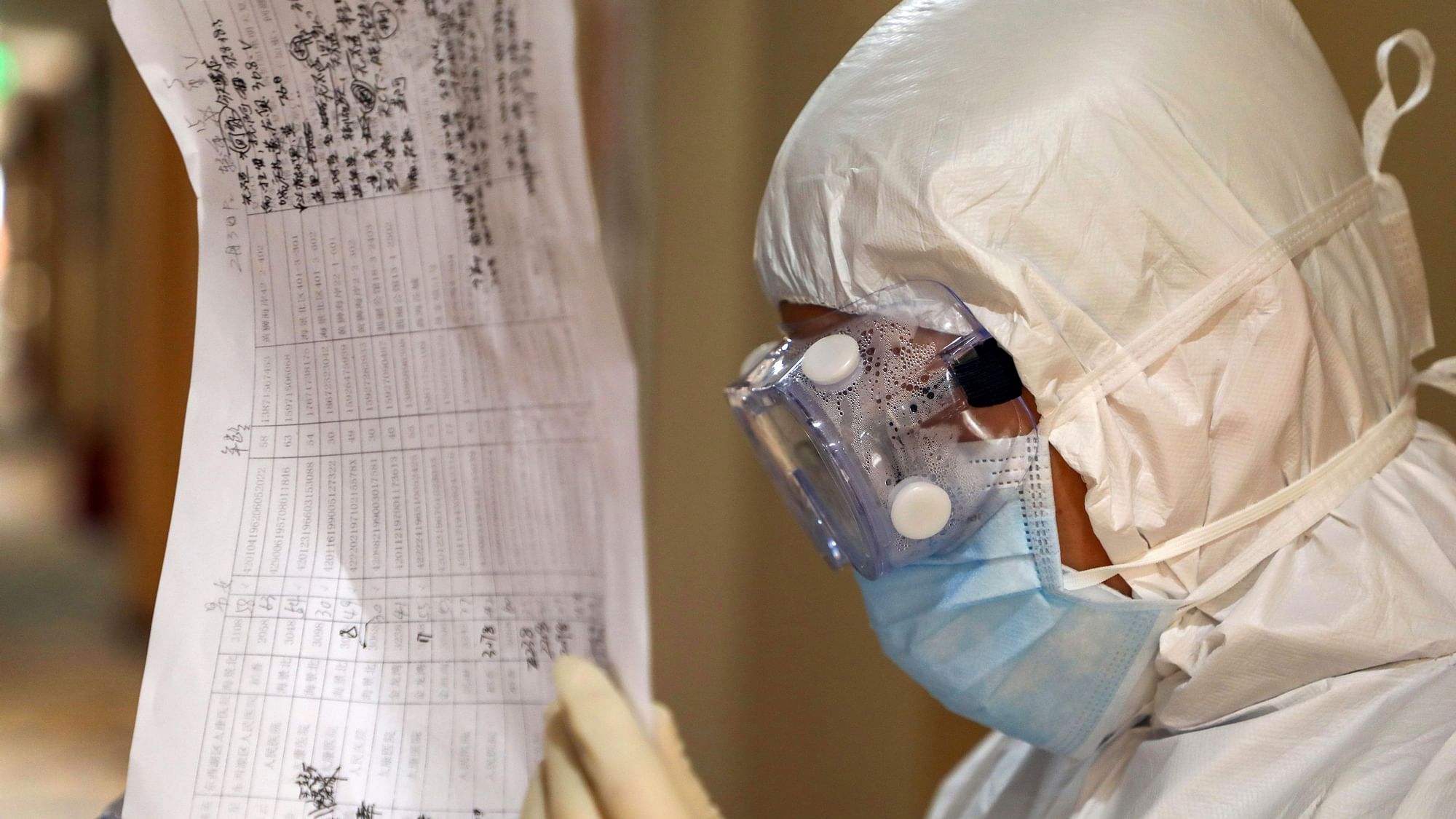 A doctor in a protective suit reads patient notes at a hotel being used for people held in medical isolation in Wuhan in central China’s Hubei province.