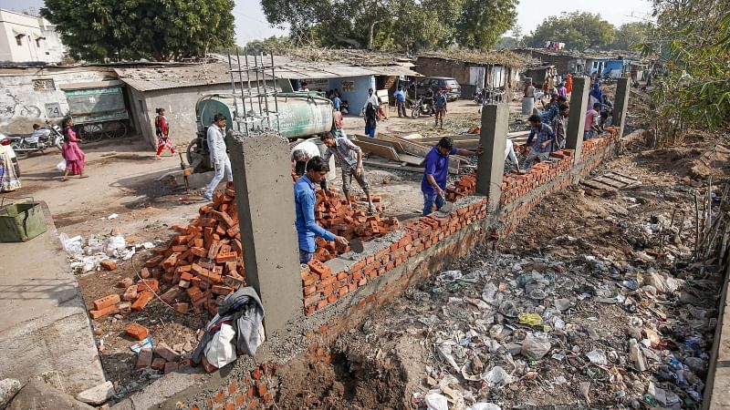 Workers construct a wall in front of a slum ahead of US President Donald Trump’s visit in Ahmedabad. 