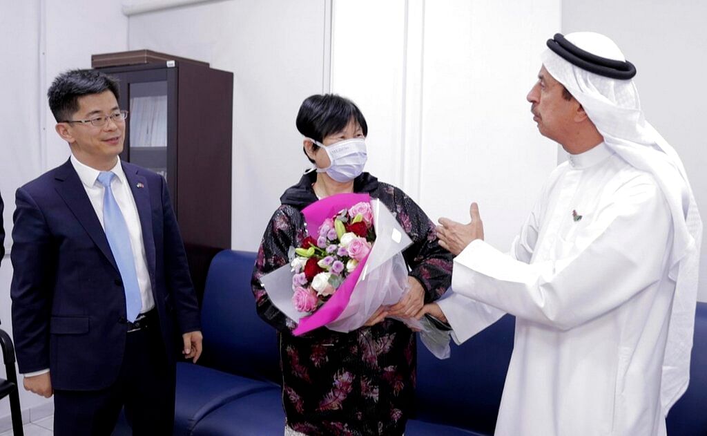 Liu Yujia, center, receives a bouquet of flowers from Dr. Hussein Al Rand, an under-secretary at the Ministry of Health, after she tested negative for the Coronavirus, as Consul General Li Xuhang of China looks on, in Abu Dhabi, United Arab Emirates