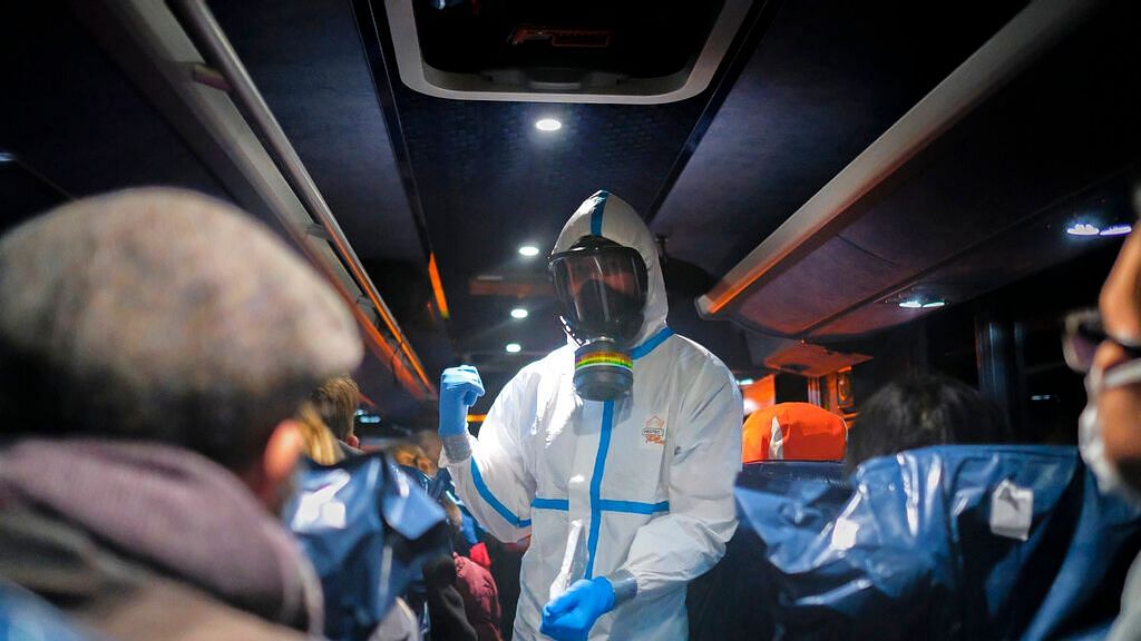 Amilitary officer wearing a protective suit gives instructions to evacuees from Wuhan, China, as they travel to a hospital after their arrival at a military base in Wroclaw, Poland.