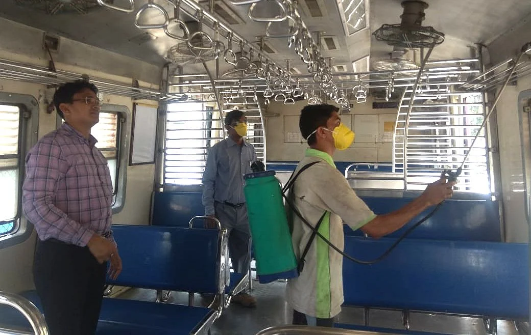 Sunil Kumar Bairwa supervises a cleaner sanitising a train coach.