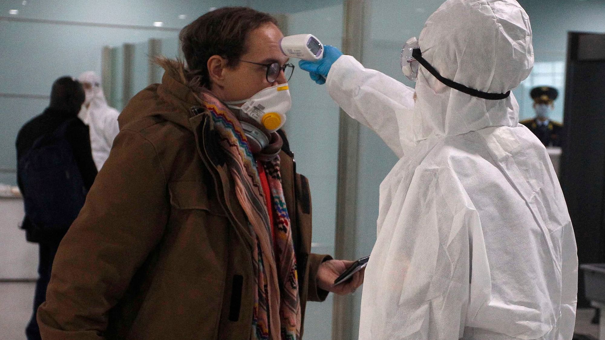 A passenger wearing a mask as a precaution against a new coronavirus has his temperature checked before boarding a flight.
