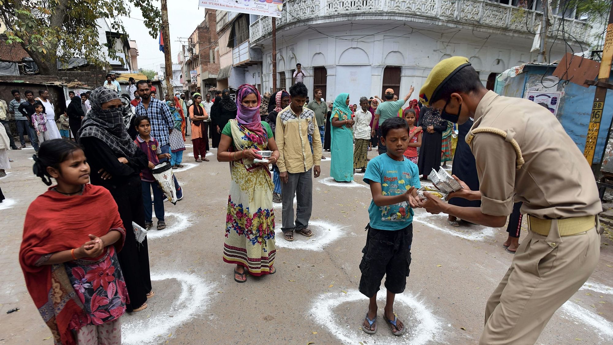 People maintain social distance as they stand in a queue to collect food, distributed by a police personnel, during day-3 of a nationwide lockdown, imposed in the wake of the coronavirus pandemic, in Prayagraj, Allahabad