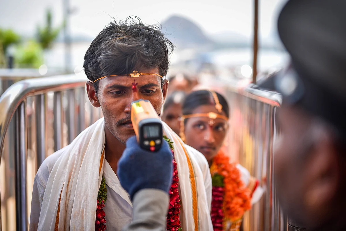 Security personnel conducts thermal screening on a newlywed couple in the wake of coronavirus pandemic, at the entrance of Kanaka Durga temple in Vijayawada, Friday, 20 March 2020.
