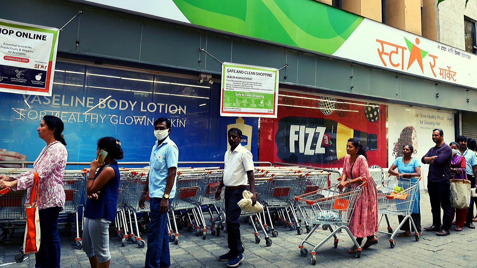 A file image of people wearing face masks in the wake of coronavirus pandemic standing in a queue to buy groceries, at Churchgate in Mumbai.