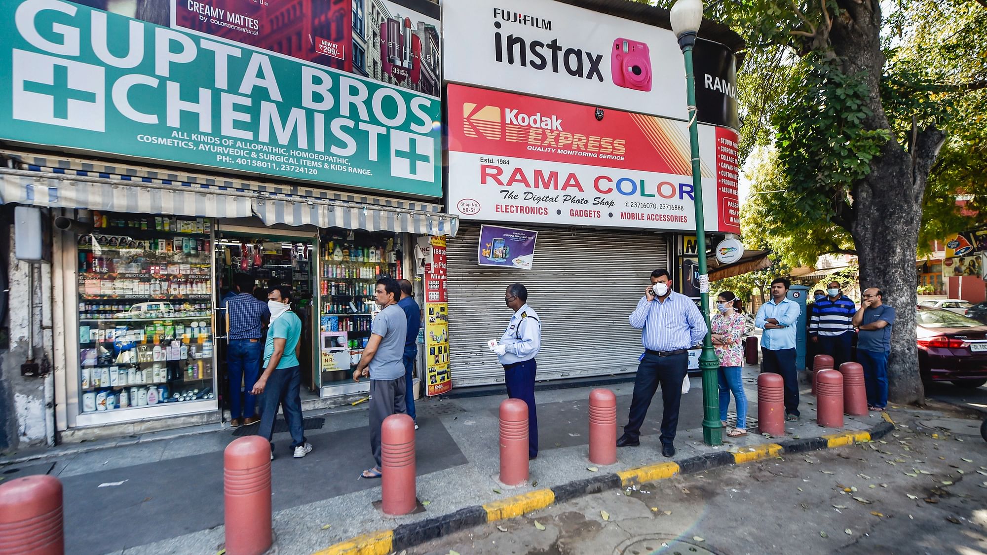 People stand in a queue outside a chemist shop while maintaining social distancing, during a nationwide lockdown in the wake of coronavirus pandemic, in New Delhi,