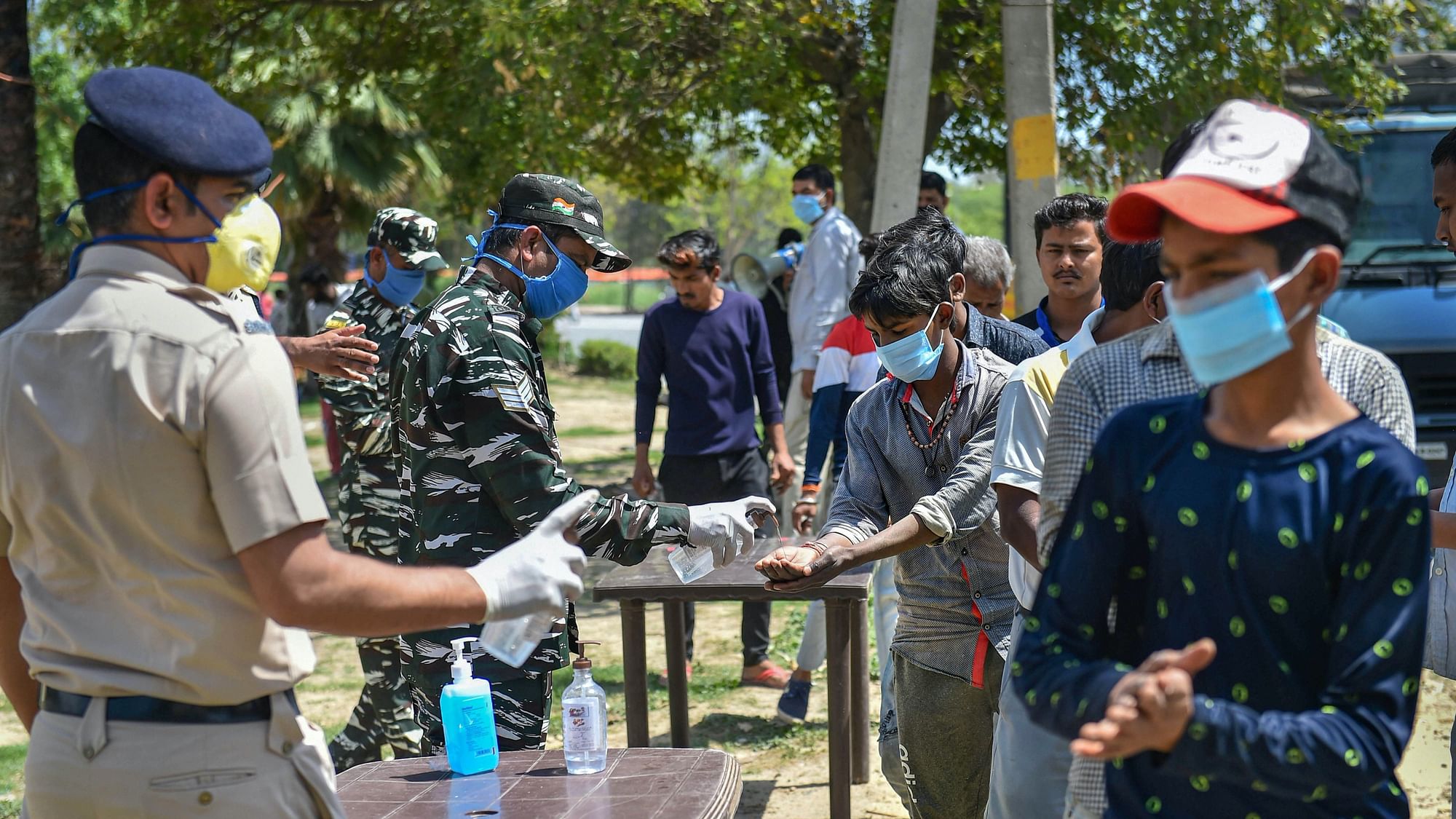  CRPF personnel pump hand sanitiser on the hands of people during a nationwide lockdown, imposed in the wake of coronavirus pandemic, in New Delhi, Monday,  30 March.