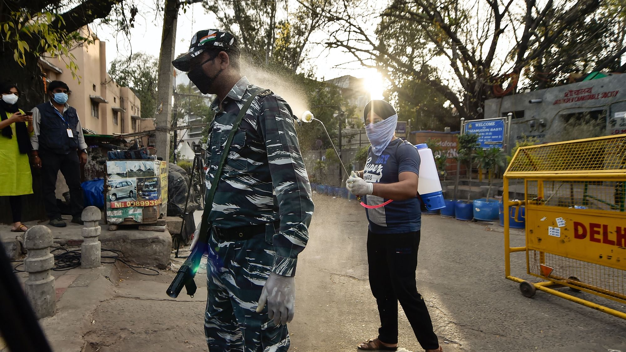  A volunteer sprays disinfectant on paramilitary personnel as they cordon off an area in Nizamuddin, Delhi. Image used for representation only.