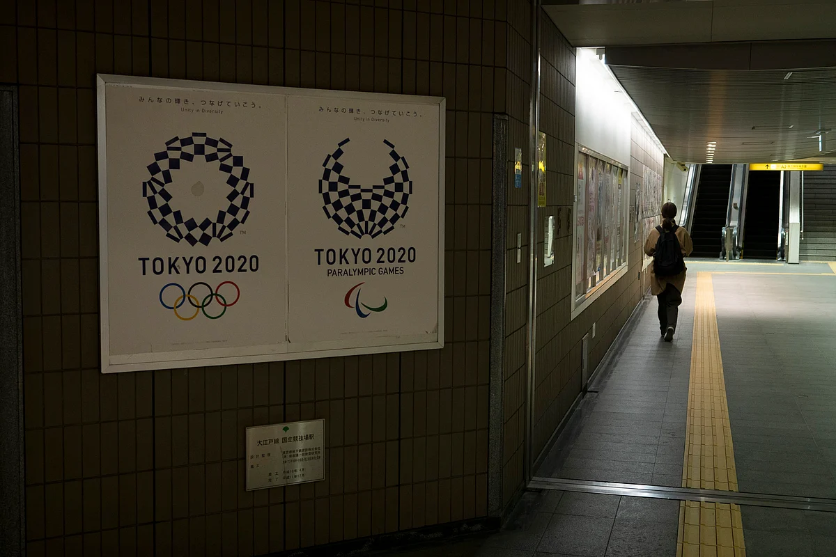 A commuter leaves a train station adorned with posters promoting the Tokyo 2020 Olympics in Tokyo, Monday, March 23, 2020.