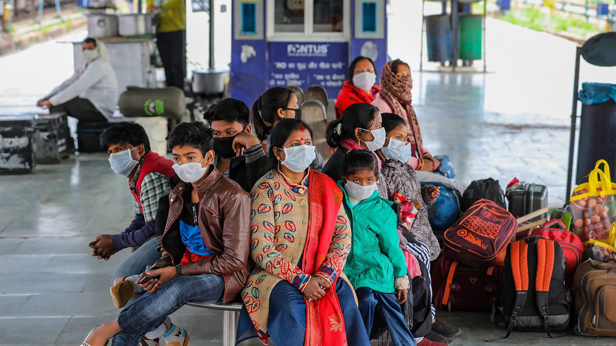 Passengers wearing protective face masks wait at a railway station following cancellation of trains in the wake of coronavirus pandemic in Jammu, Saturday, March 21, 2020.&nbsp;