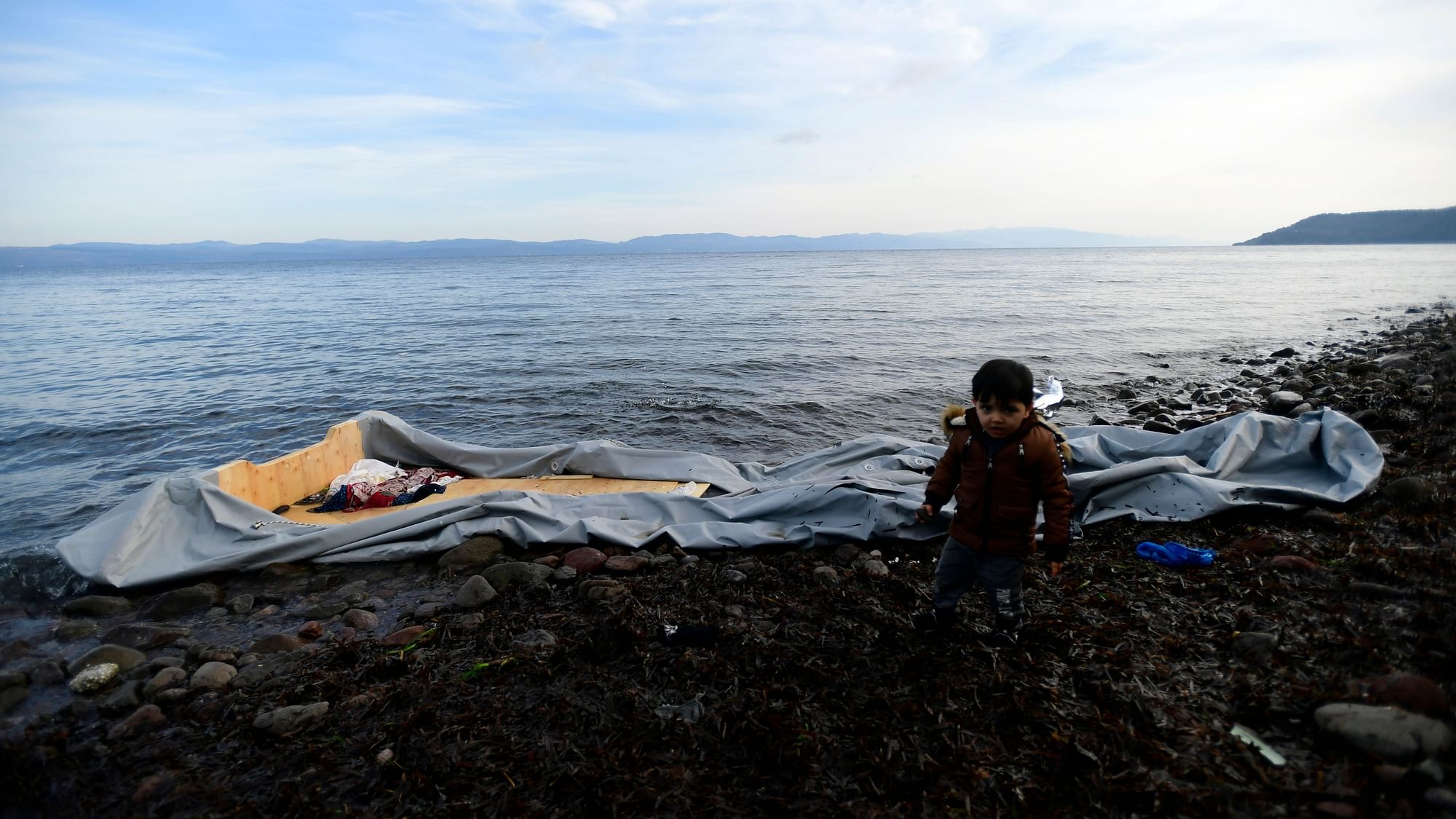A boy stands next to a dinghy at the village of Skala Sikaminias, on the Greek island of Lesbos, after crossing with other migrants the Aegean sea from Turkey, Sunday, 1 March.&nbsp;&nbsp;