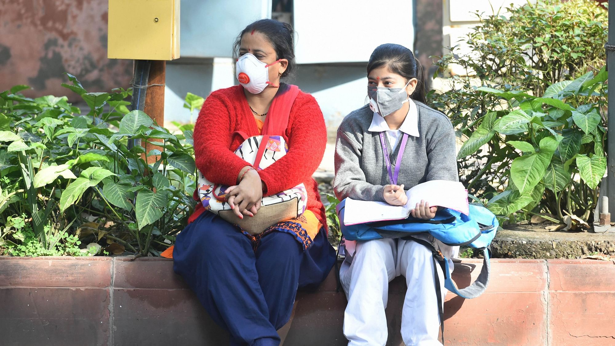 A student with her family member wear masks amid coronavirus fears, as they wait outside Kerala School ahead for their CBSE Class 10 exams, in New Delhi, Wednesday, March 18, 2020