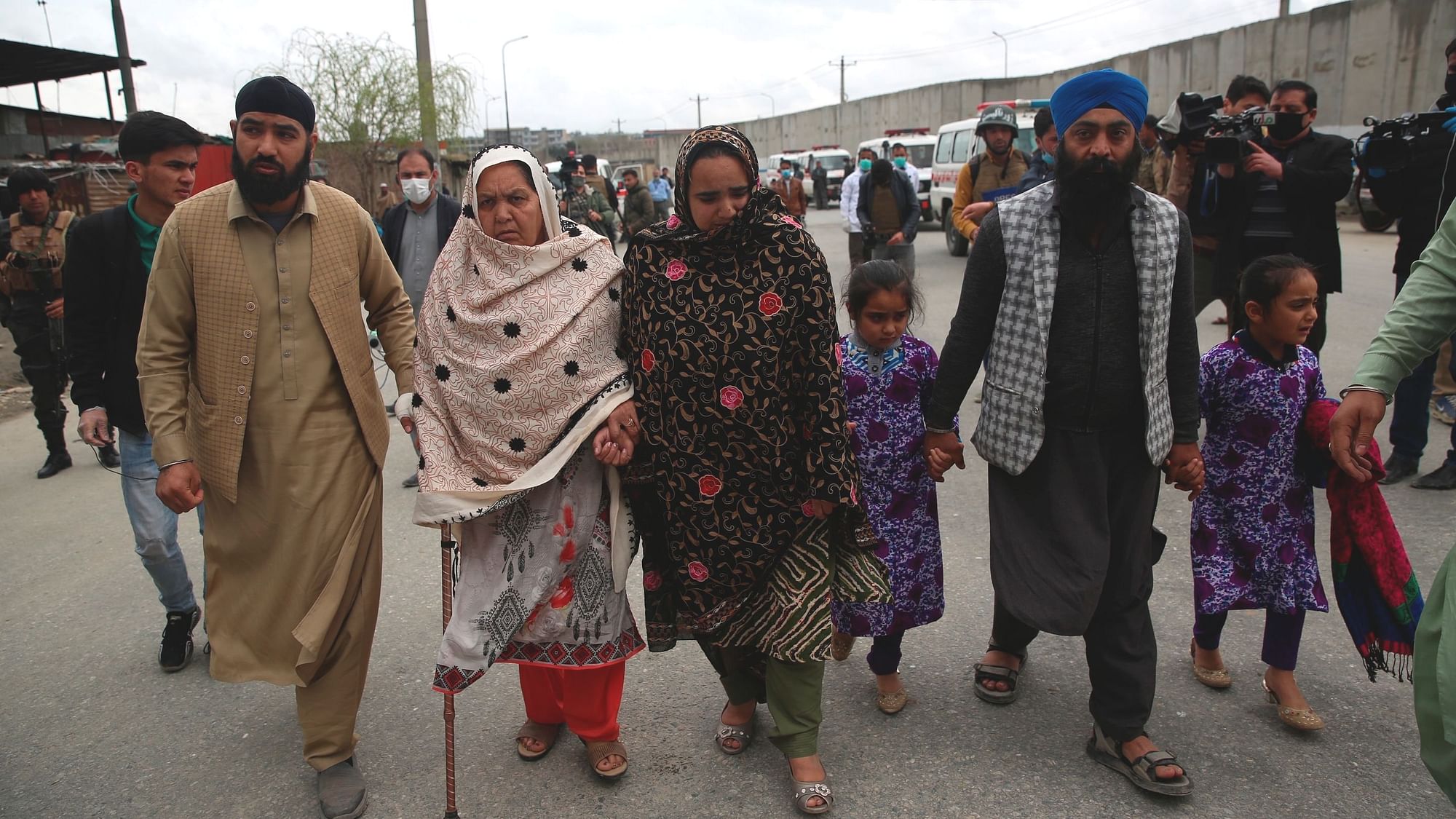 Family members walk through the site of an attack in Kabul, Afghanistan, Wednesday, 25 March.