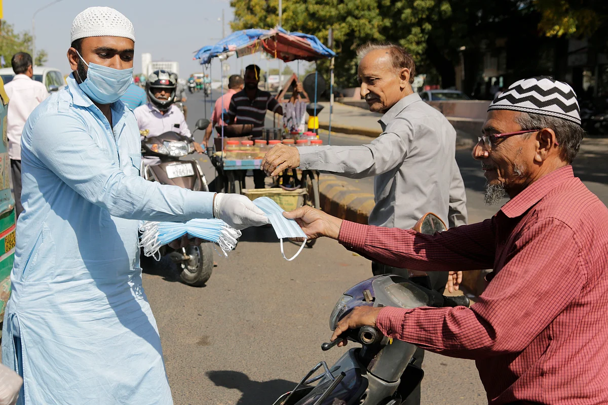 A man distributes face masks to motorists and others to be used as a precaution against COVID-19 at a traffic intersection in Ahmedabad, India, Friday, 20 March 2020.