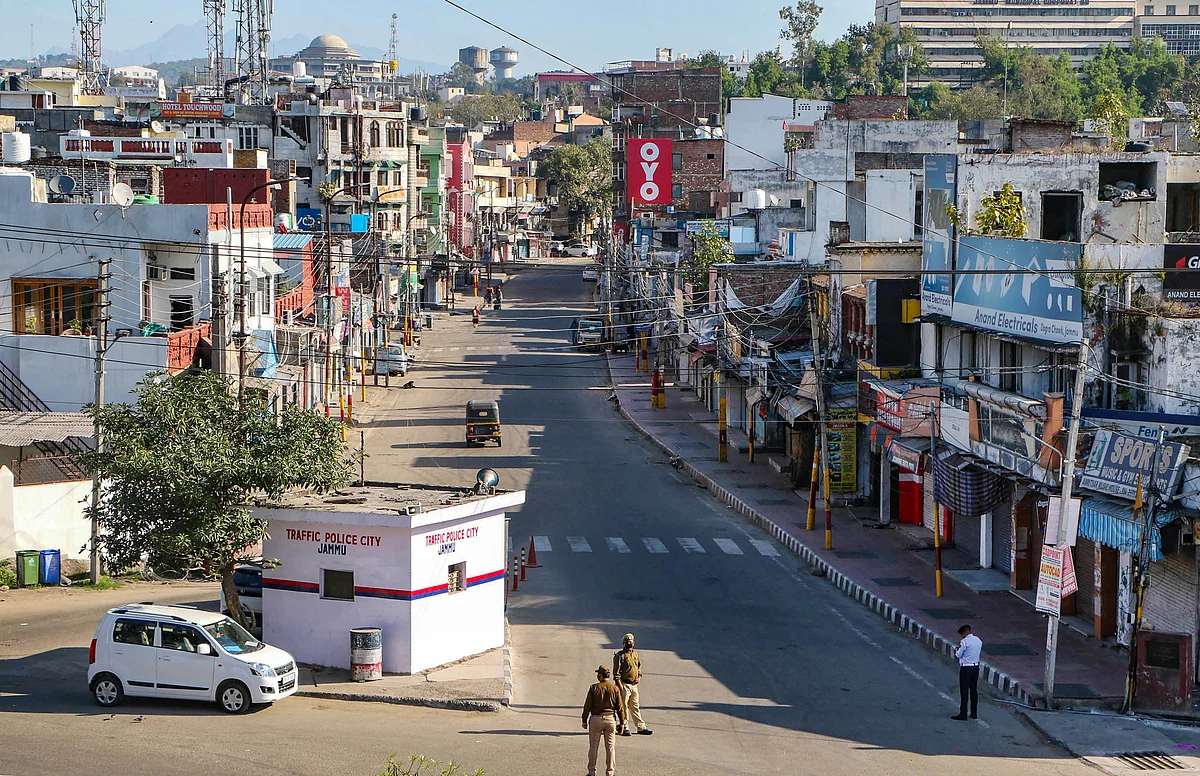 Security personnel wearing protective face mask stand guard on a deserted city street in Jammu.