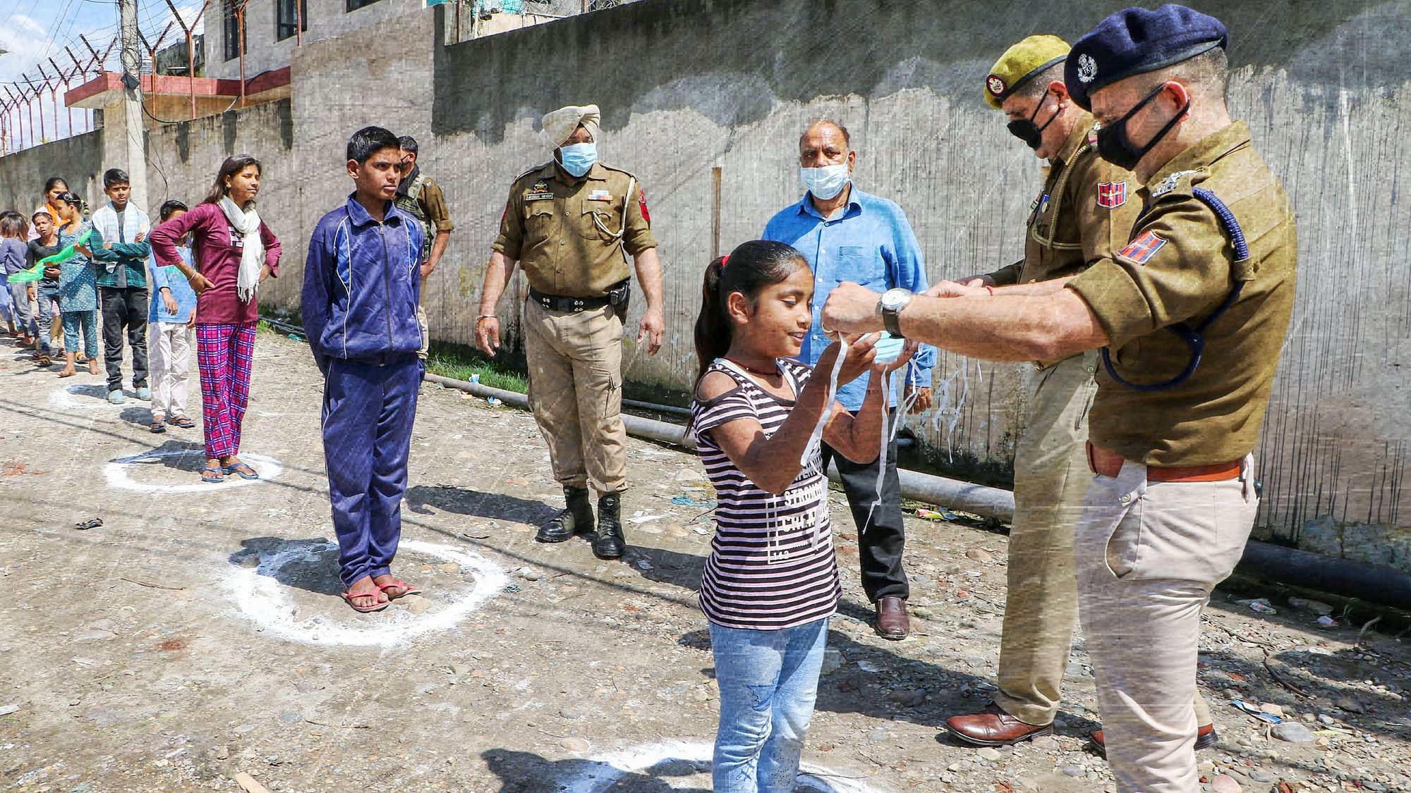 Police distribute masks among people during a nationwide lockdown, in Jammu, Saturday.